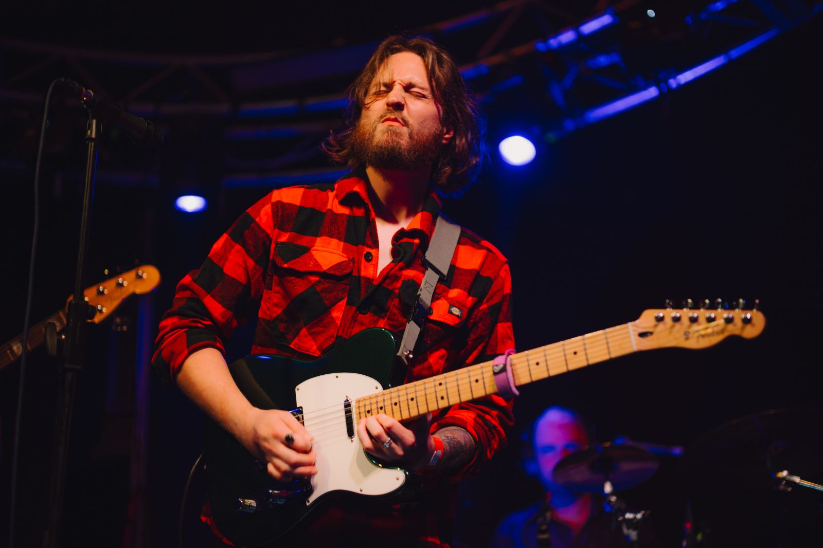 Neil Potter performing live on stage, passionately playing guitar and singing from his debut album.